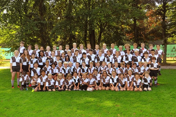 Kinder sitzen und stehen in vier Reihen hintereinander auf einem Rasen. Sie tragen Trikots vom FC St. Pauli. Kinder sitzen und stehen in vier Reihen hintereinander auf einem Rasen. Sie tragen Trikots vom FC St. Pauli.