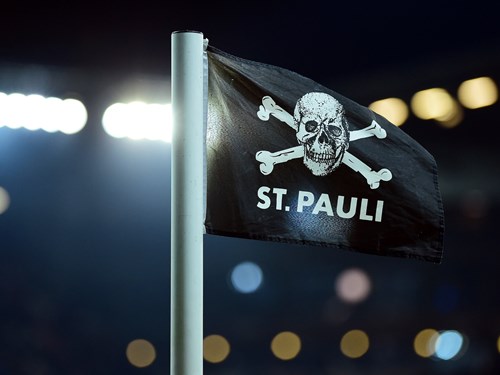 Eine schwarze Fahne an einer Stange. Auf der Fahne ist ein Totenkopf. Auf der Fahne steht St. Pauli.